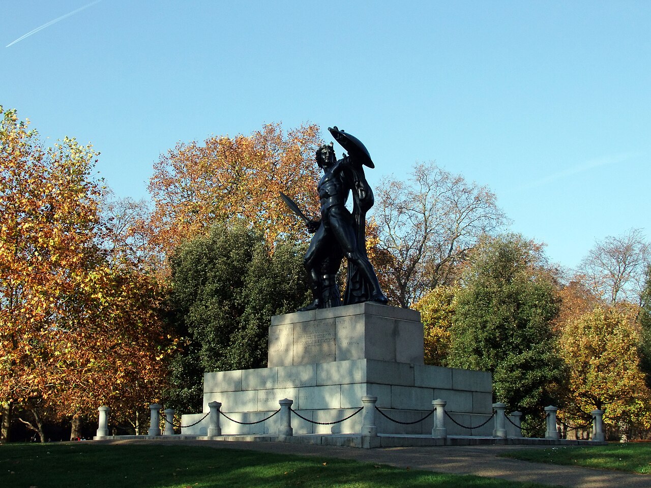 The bronze statue of Achilles with shield and sword on a large granite plinth among autumn trees, near Hyde Park Corner