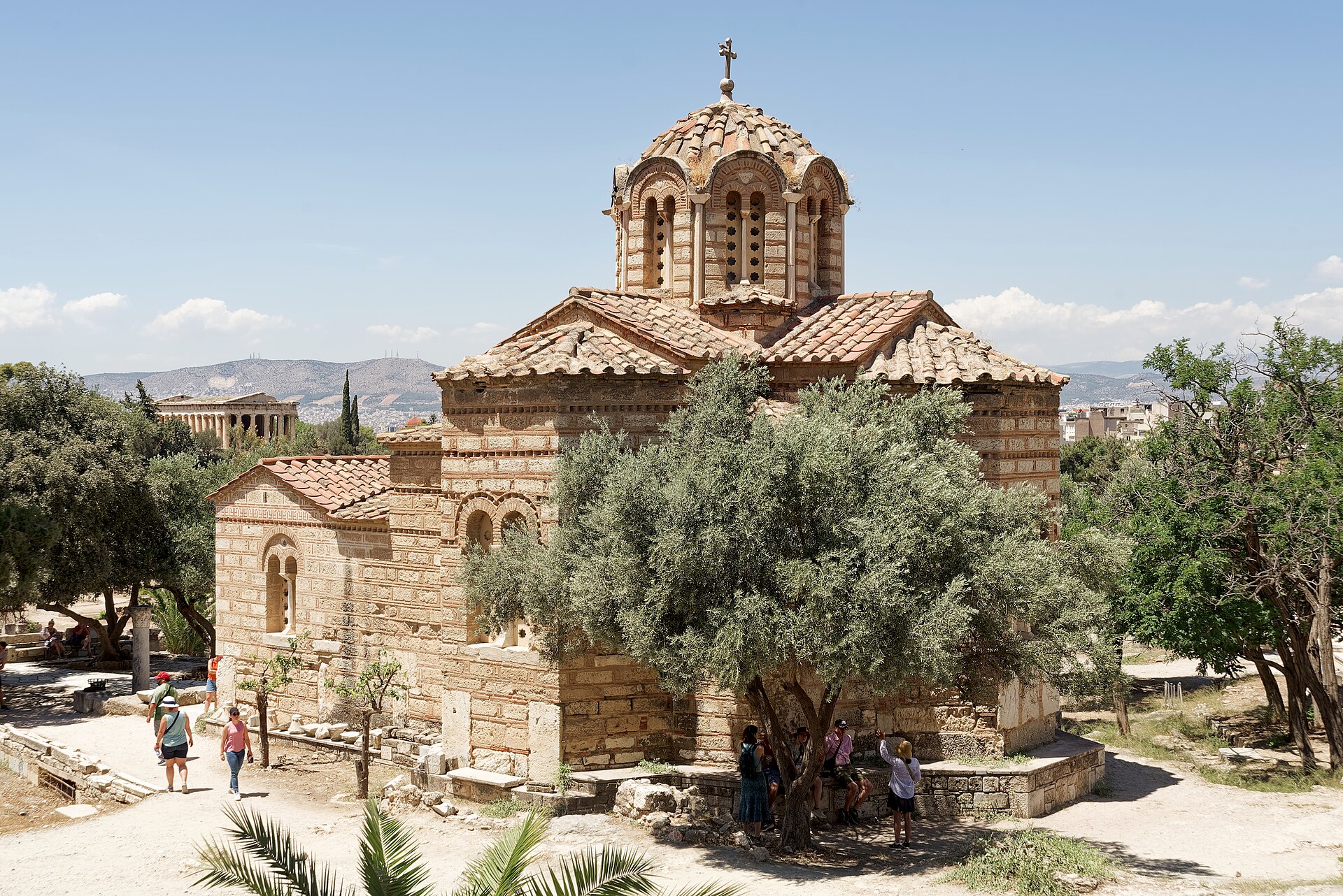 The Byzantine church of the Holy Apostles in the Ancient Agora of Athens, with its dome on a drum and its stone and brick walls; to the left, in the distance, the Temple of Hephaestus