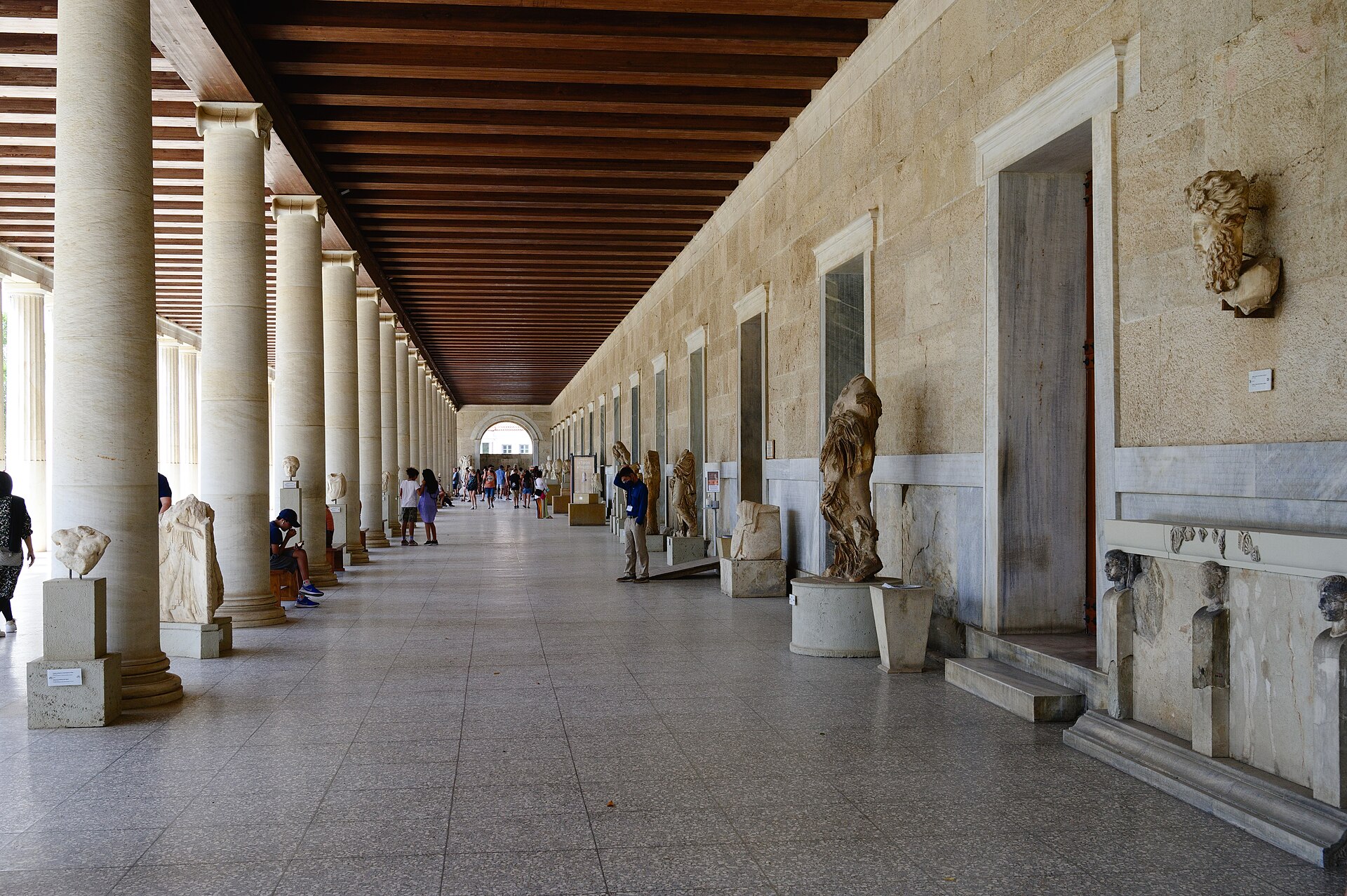 The ground-floor gallery of the Stoa of Attalos used as a museum, with statues and reliefs lined up between the columns and the wooden beamed ceiling behind
