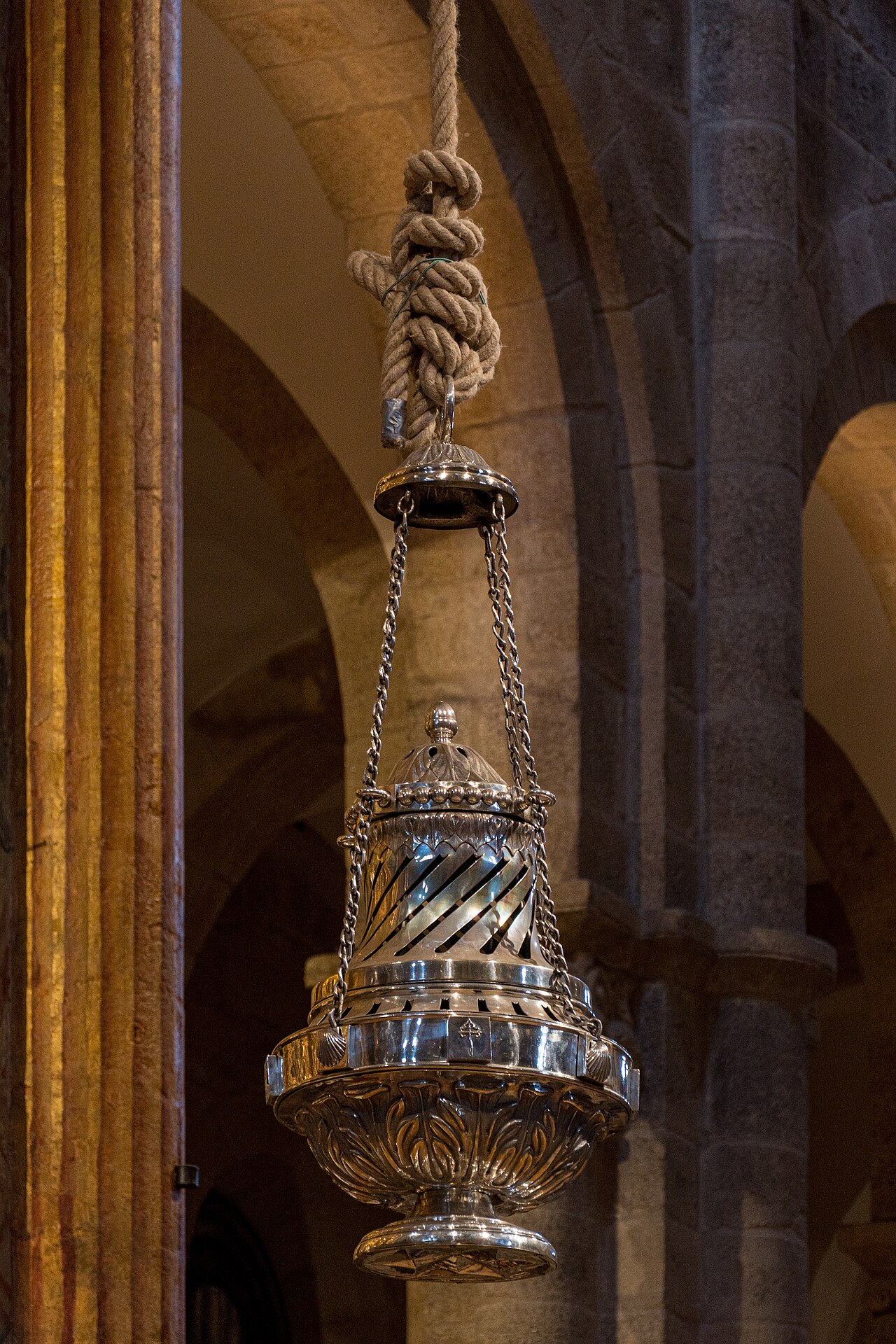 The Botafumeiro of Santiago Cathedral, a huge silver-coloured censer hanging from a thick rope between granite columns