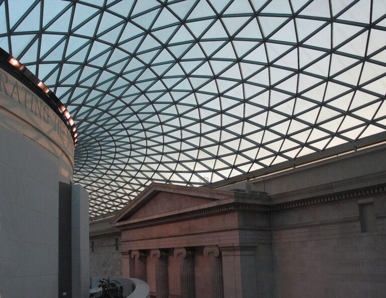 The Great Court of the British Museum: the glass and steel roof in a lattice of triangles over the courtyard, the stone drum of the Reading Room on the left and a classical portico beyond