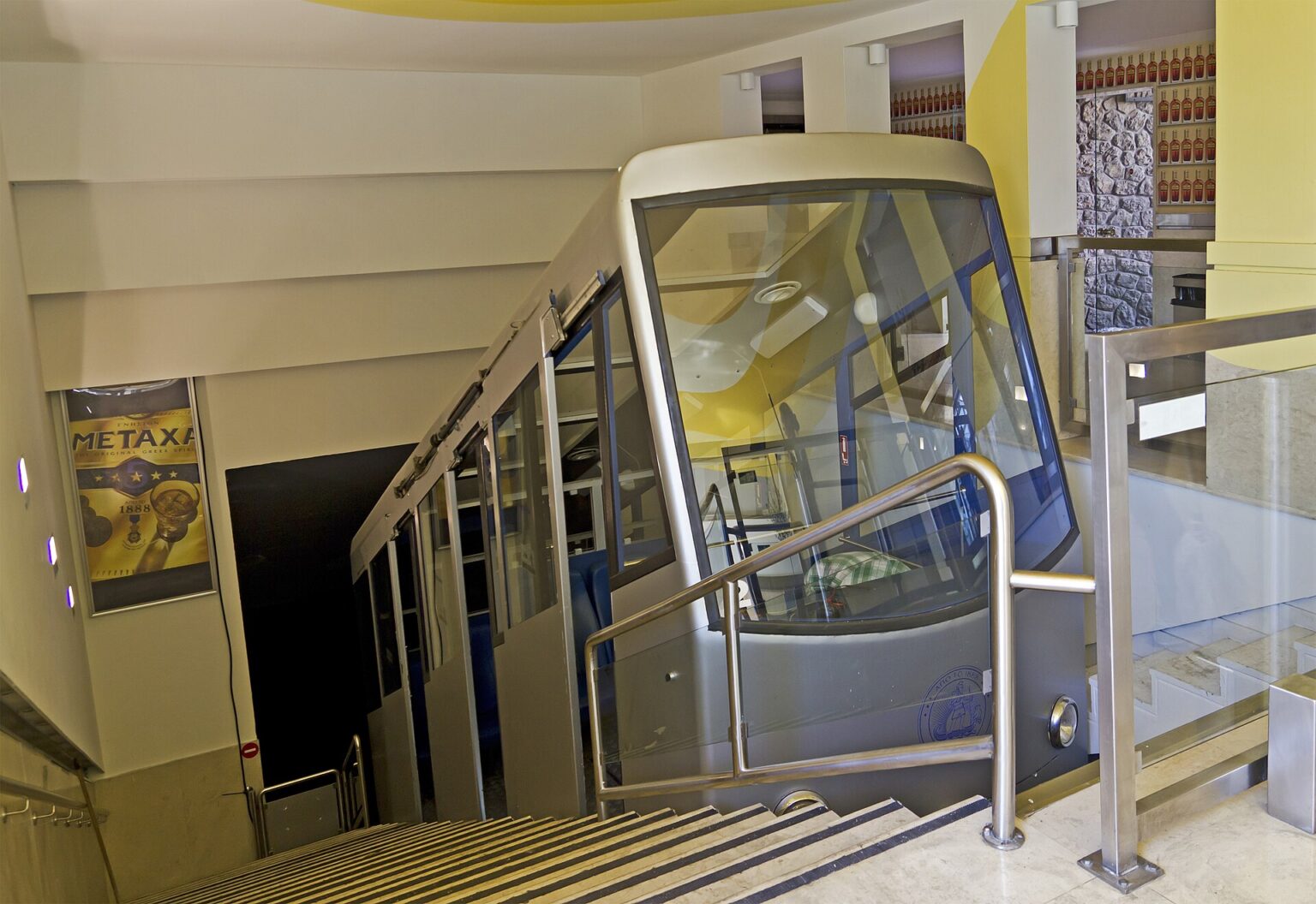 The Lycabettus funicular car standing at the upper station inside the tunnel cut through the rock, beside the staircase passengers use to get in and out