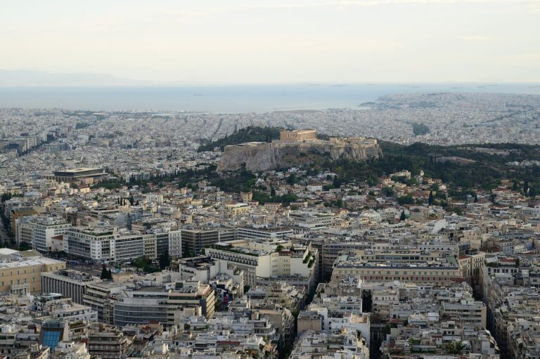 View over Athens from the summit of Lycabettus Hill: the white rooftops of the city centre, the rock of the Acropolis with the Parthenon on top and the coast of the Saronic Gulf in the distance