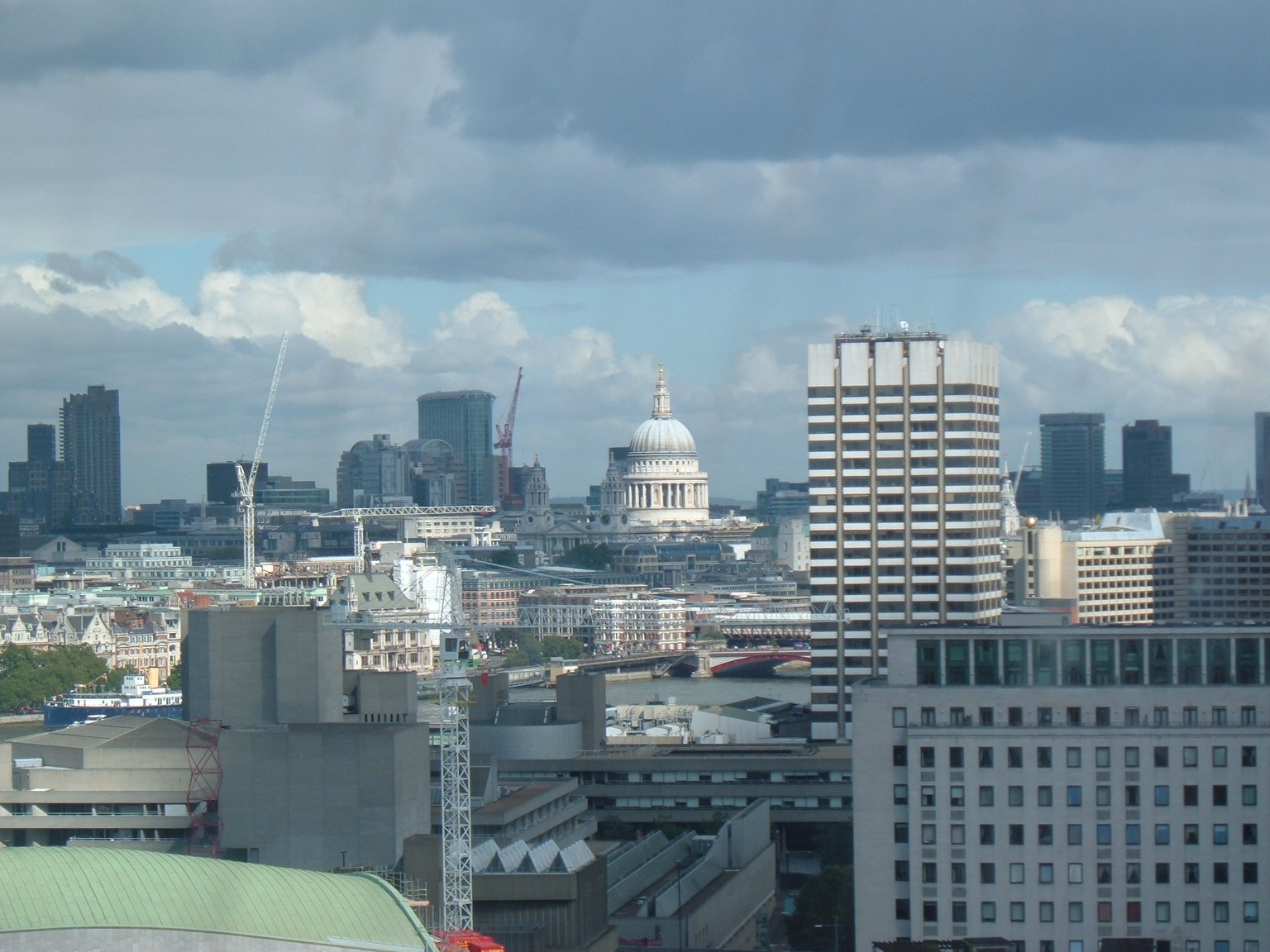 The dome of St Paul's Cathedral rising above the South Bank buildings and the towers of the City, seen from a London Eye capsule under a cloudy sky