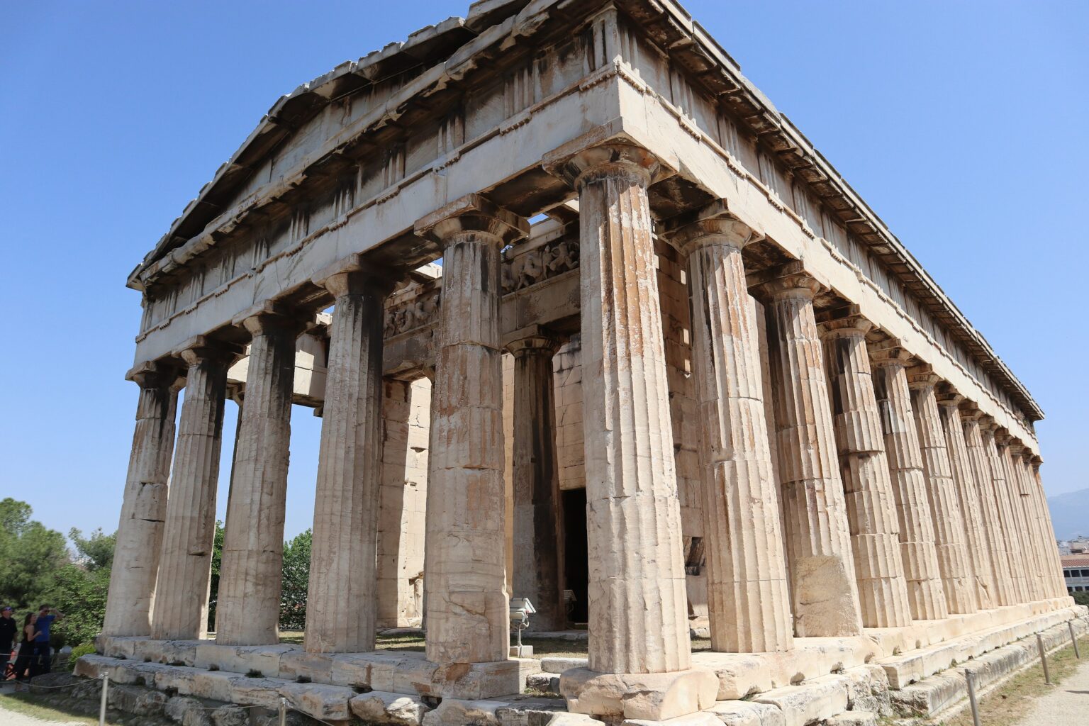 The Temple of Hephaestus in Athens seen from one corner, with its triangular pediment, the Doric columns of the front and the whole row down the flank, and the entablature and part of the roof still in place