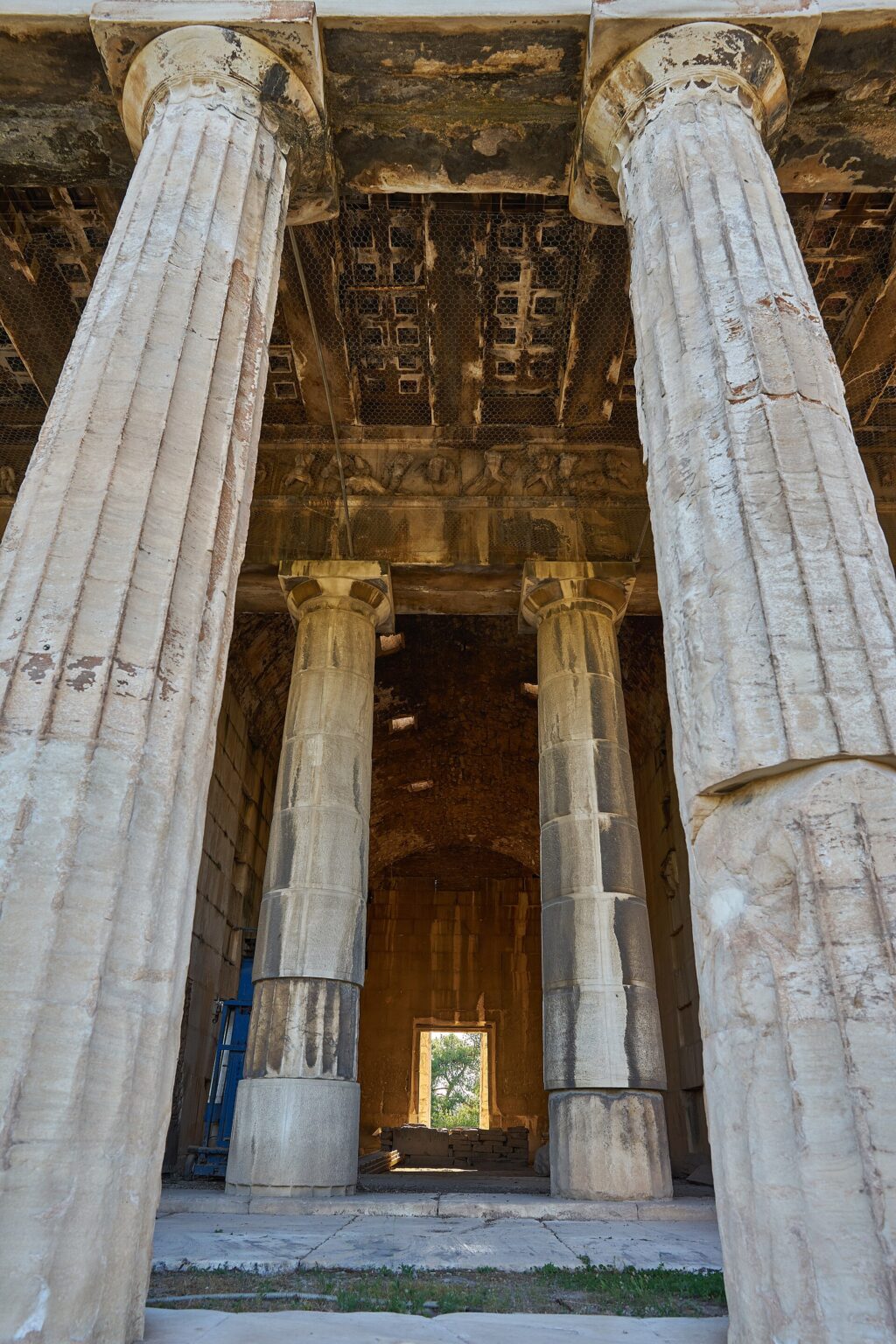 Looking into the Temple of Hephaestus between two columns of the peristyle: the coffered marble ceiling, the carved frieze, the two columns of the porch and, beyond them, the whole cella as far as the doorway at the far end