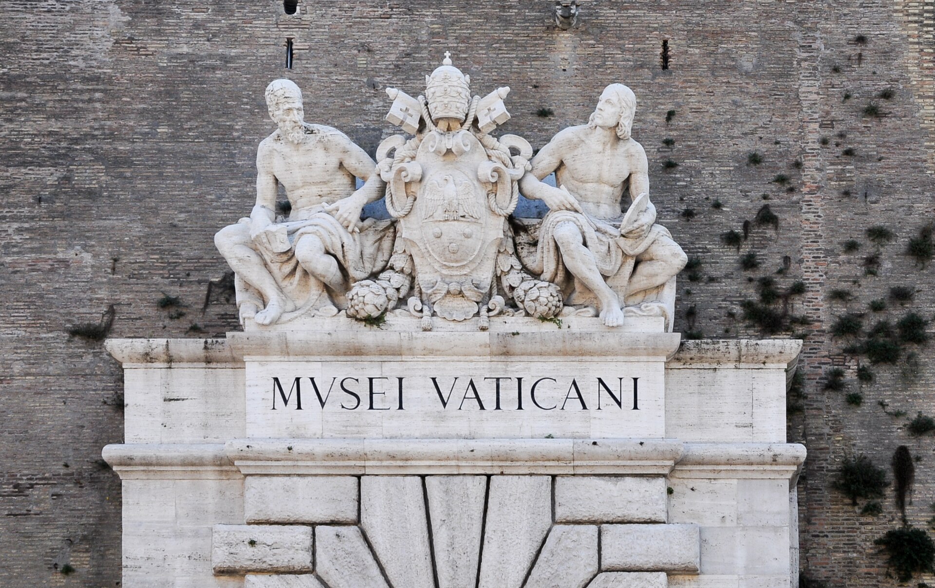 The monumental doorway of the Vatican Museums on Viale Vaticano, with the sculpted figures of Michelangelo and Raphael above it