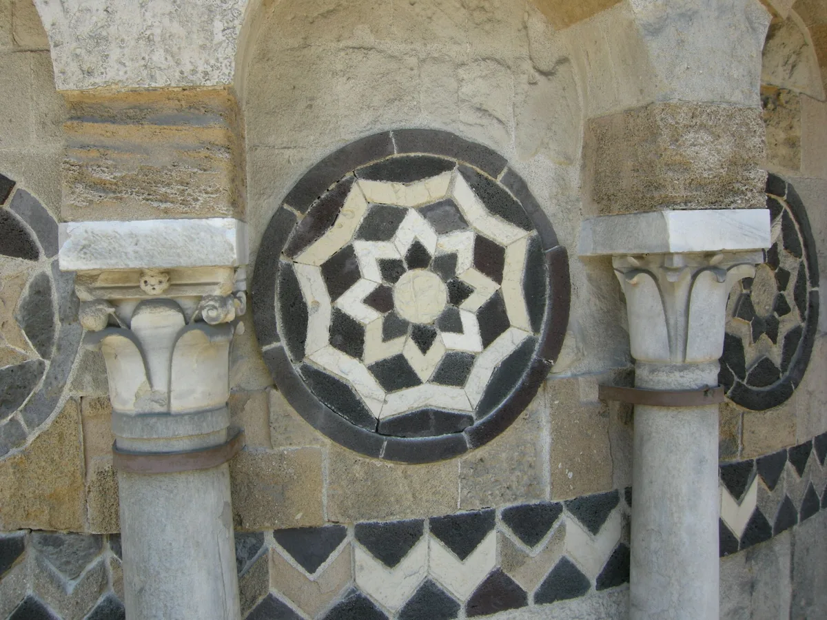 Polychrome stone inlays on the apse of the Church of the Catalans in Messina: star-shaped rosettes between small columns with carved capitals