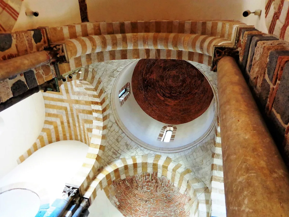 Looking up at the dome and the striped arches of the crossing inside the Church of the Catalans in Messina