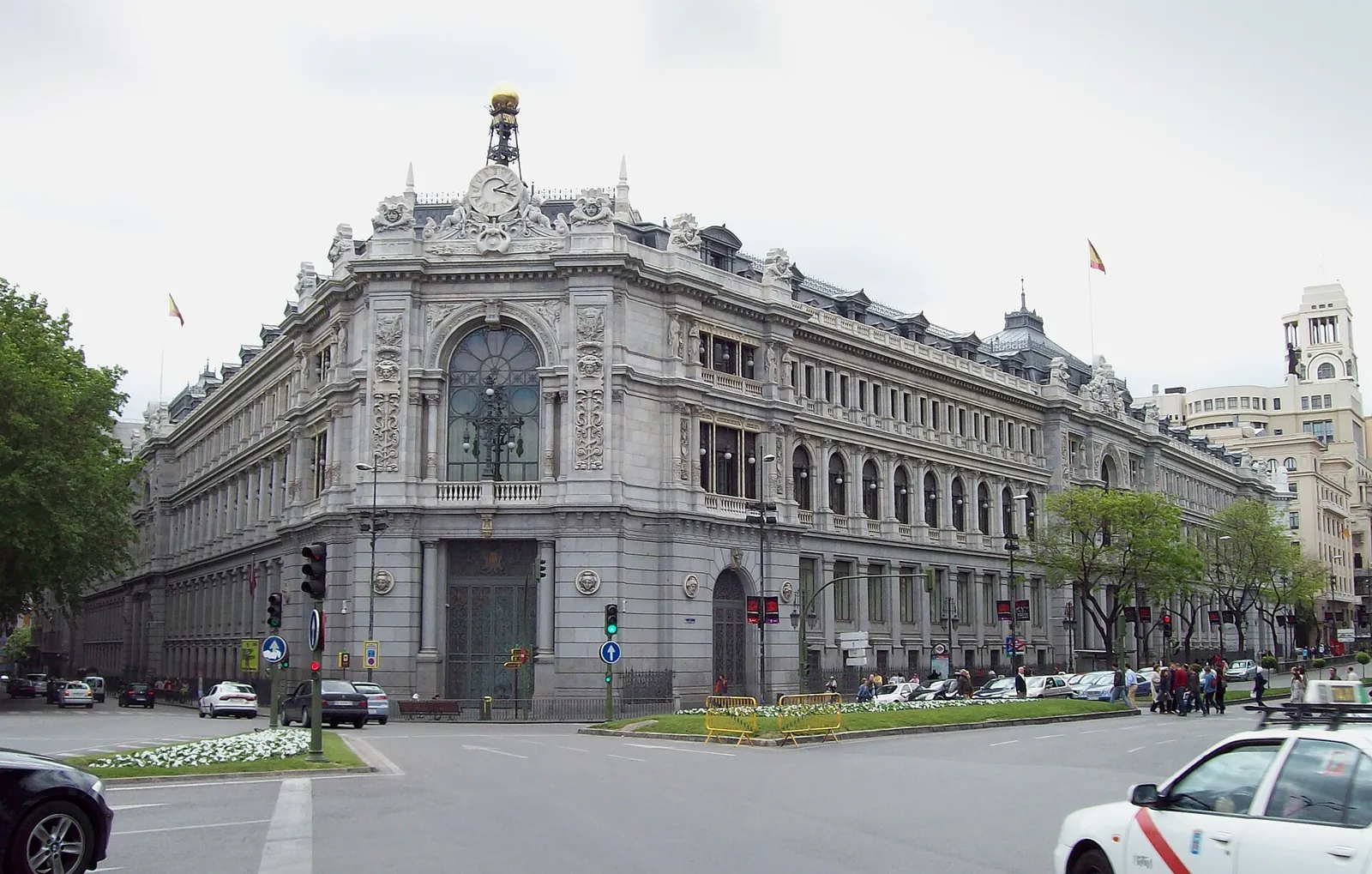 The Bank of Spain building on the corner of Plaza de Cibeles, with its stone corner facade and a large clock topped by a golden ball above the entrance