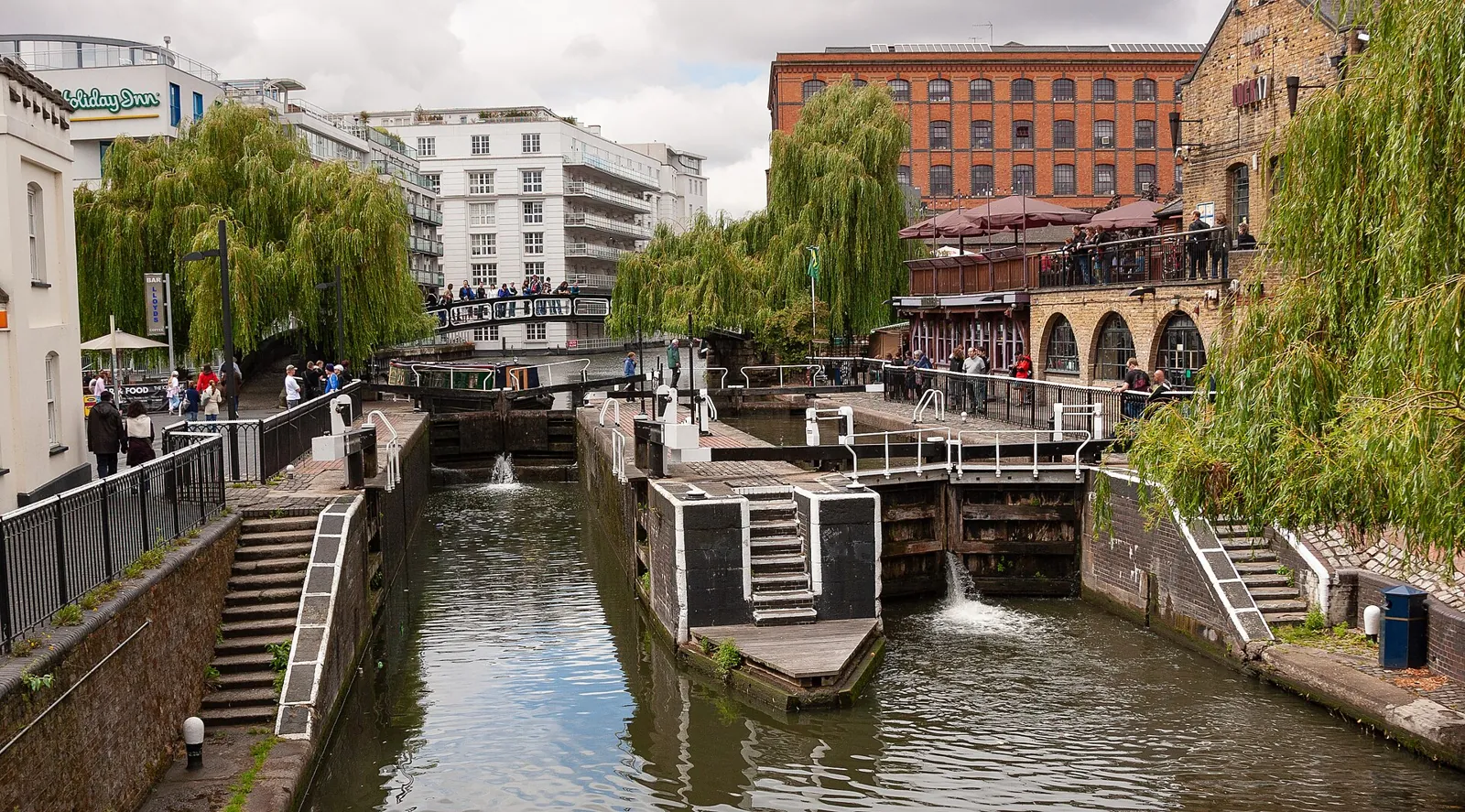 The twin locks of Camden Lock on Regent's Canal seen from the road bridge, with willows and brick buildings