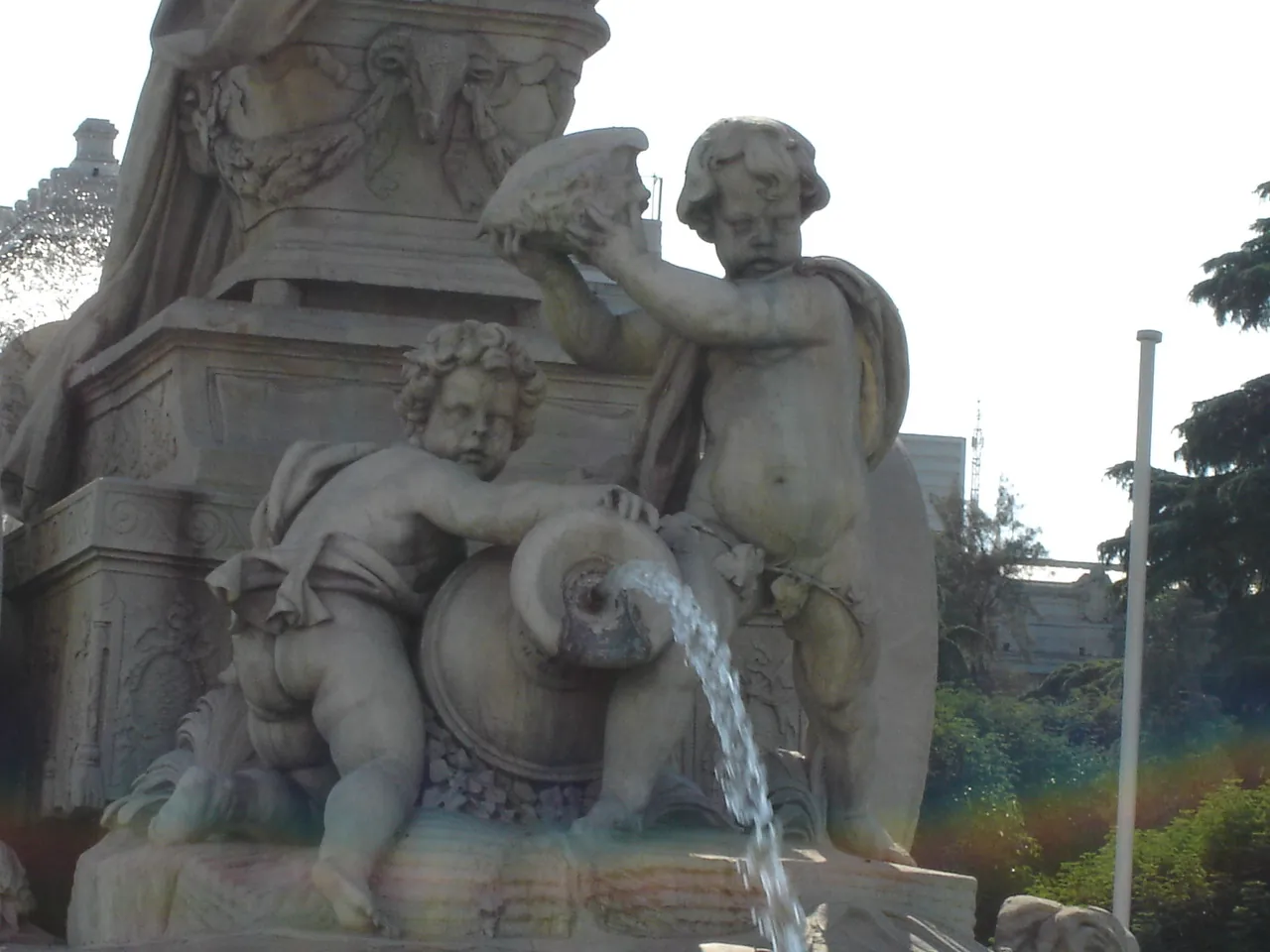 The 2 marble children at the back of the Cibeles Fountain: one kneeling with a jar pouring water and one standing and holding up a conch shell