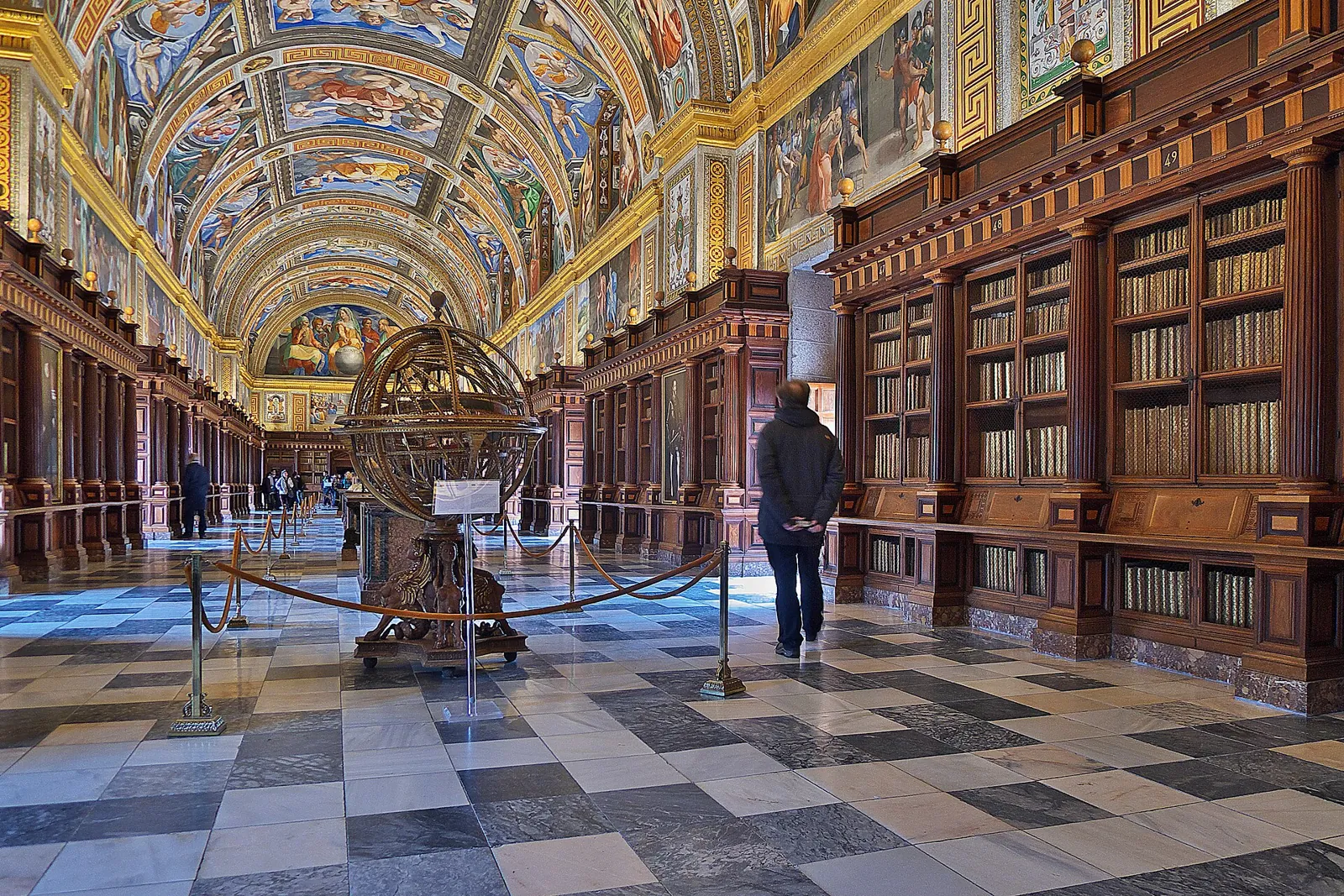 Main hall of the Royal Library of El Escorial, with its frescoed barrel vault, dark wooden bookcases and marble floor