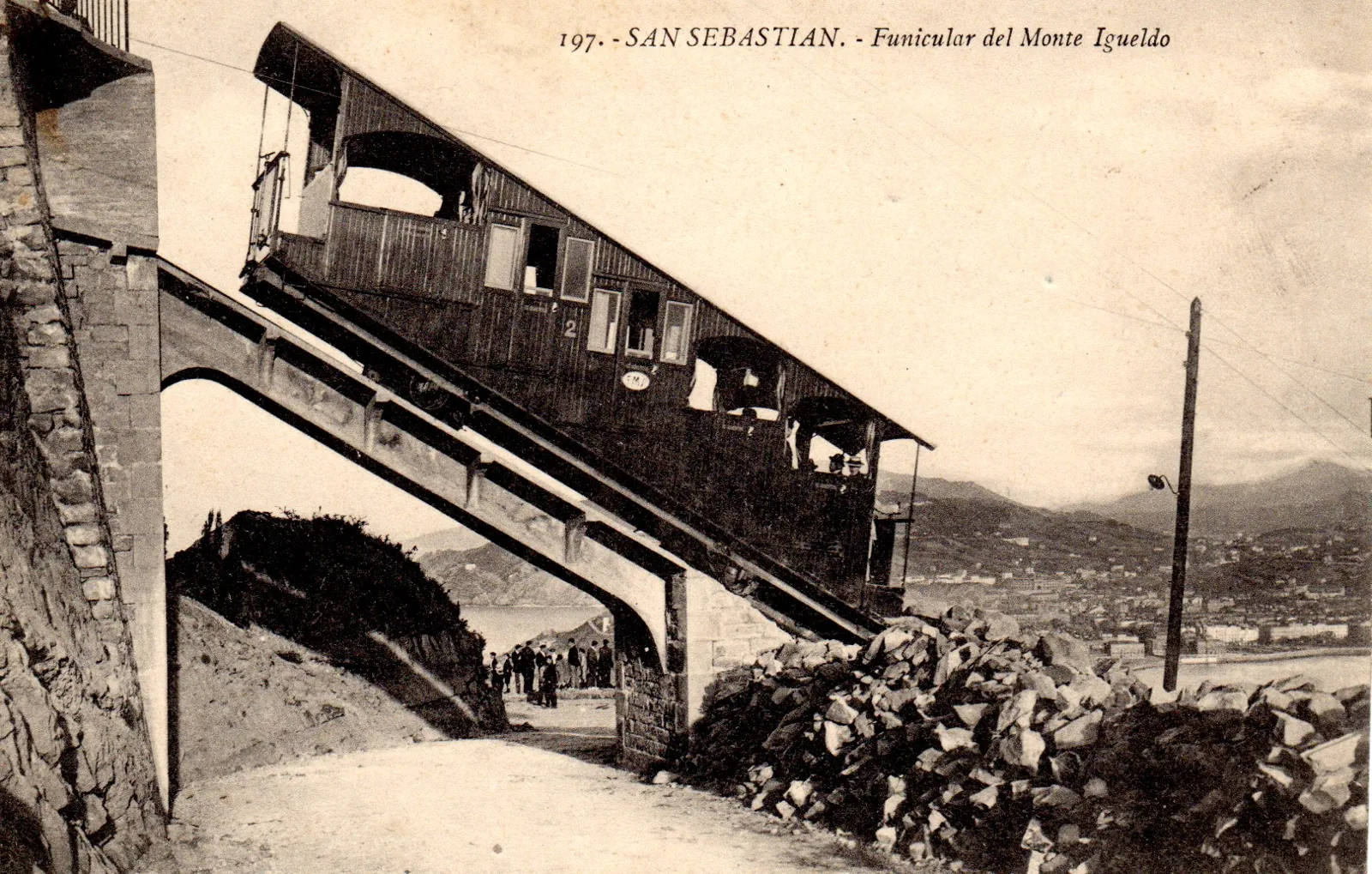 Old black-and-white postcard of the Monte Igueldo funicular: a car climbing the hillside over a bridge on the line