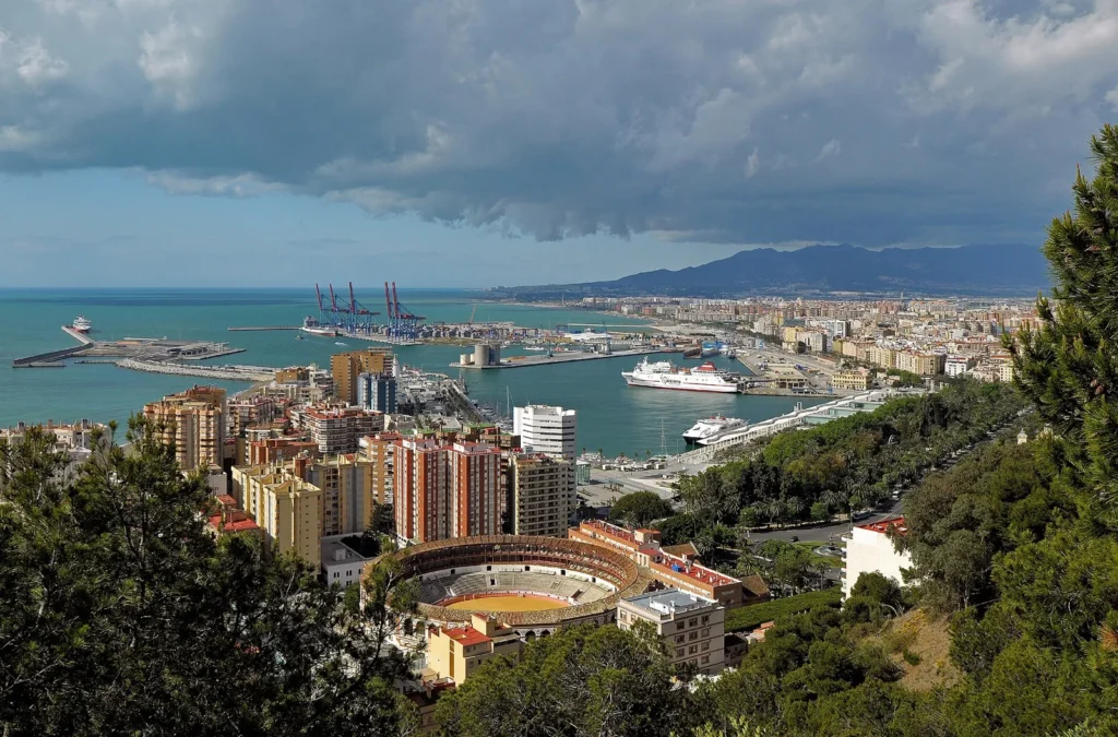 View from Gibralfaro over Málaga: the bullring in the foreground, apartment blocks, the port with a ferry and the sea