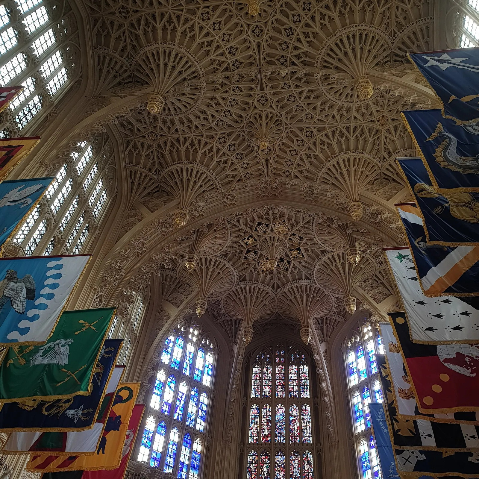 The pierced stone fan vault of the Henry VII Lady Chapel, with the colourful banners of the Order of the Bath and stained glass