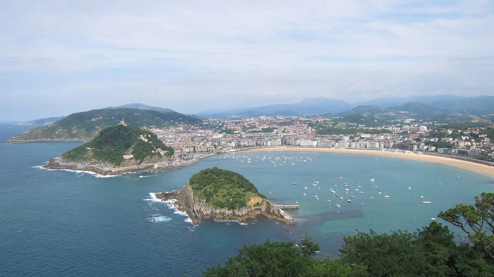 La Concha Bay seen from above: Santa Clara Island in the middle, Mount Urgull on the left and the curve of the beach with the city behind