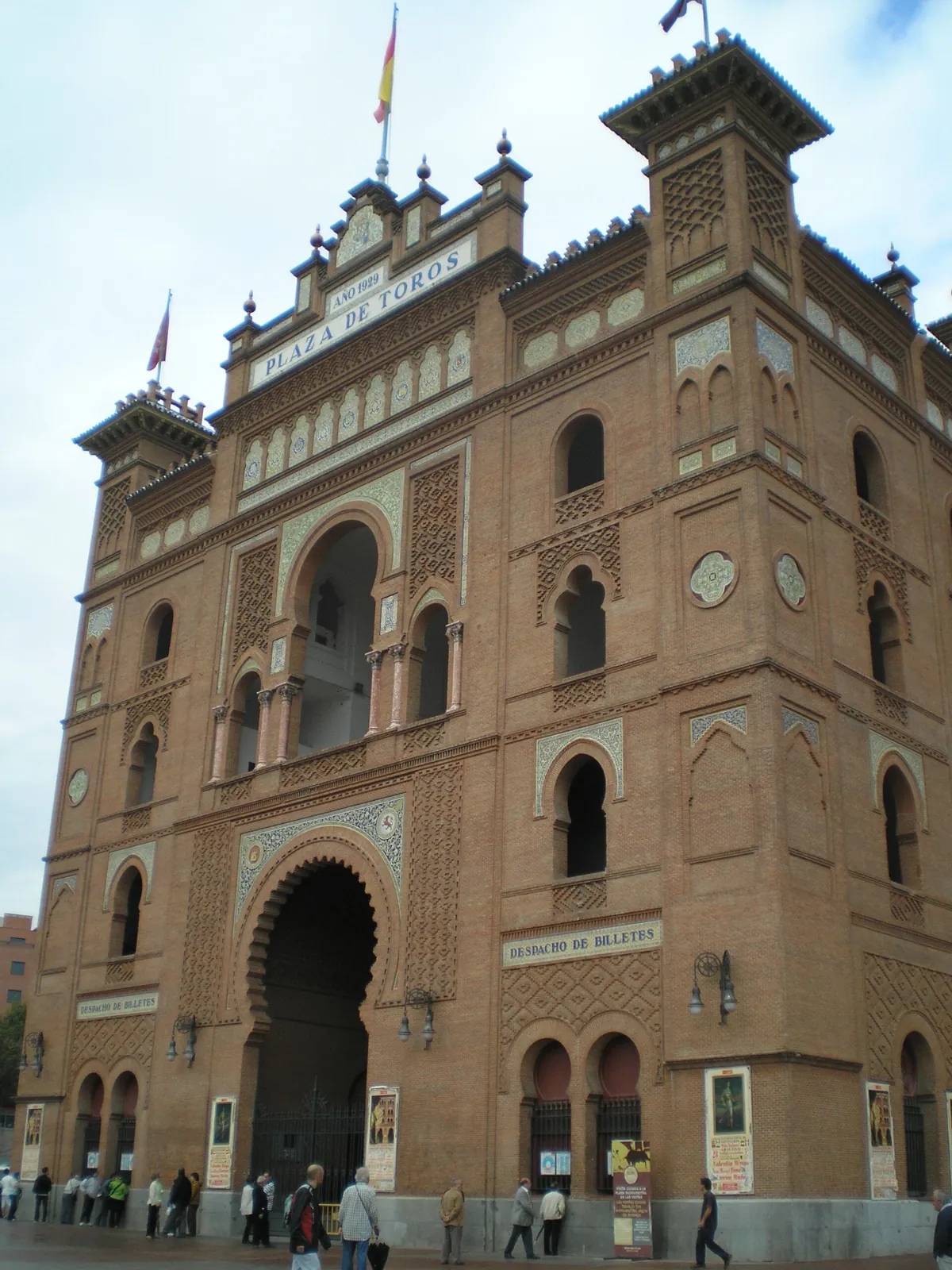 Central tower of Las Ventas with the large horseshoe arch of the Puerta Grande, the Plaza de Toros sign and flags on top