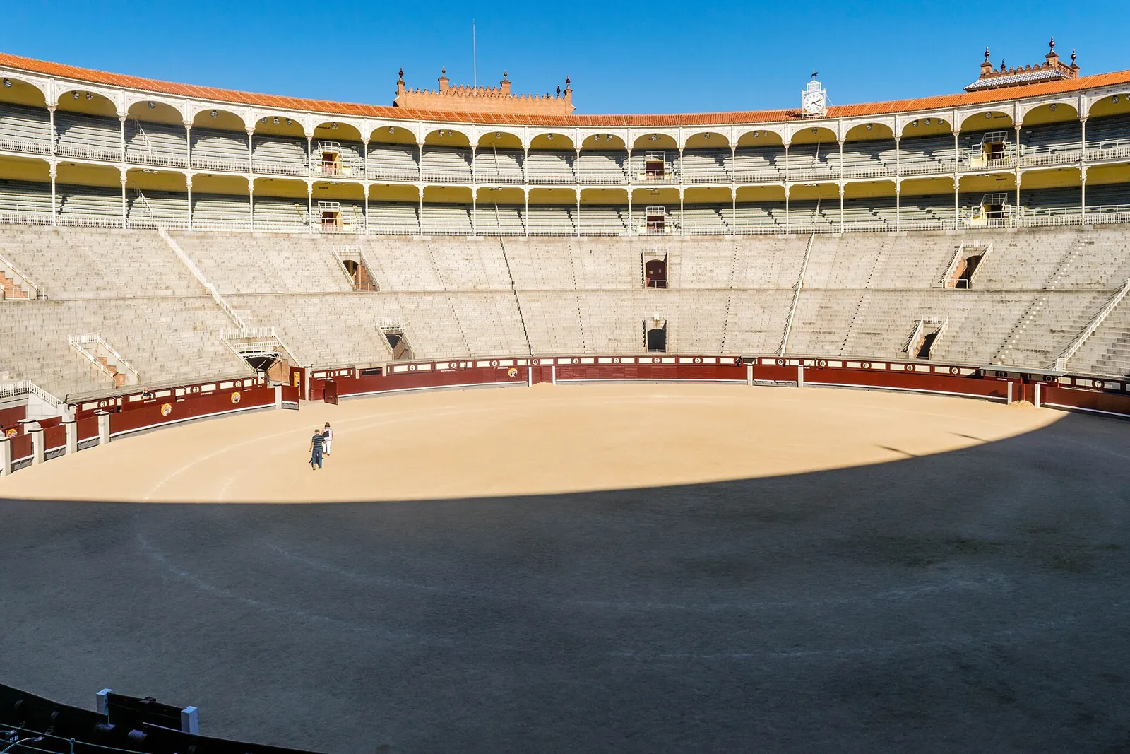 Empty interior of Las Ventas: the sand ring, the red barrier and the stone stands below the arched upper galleries