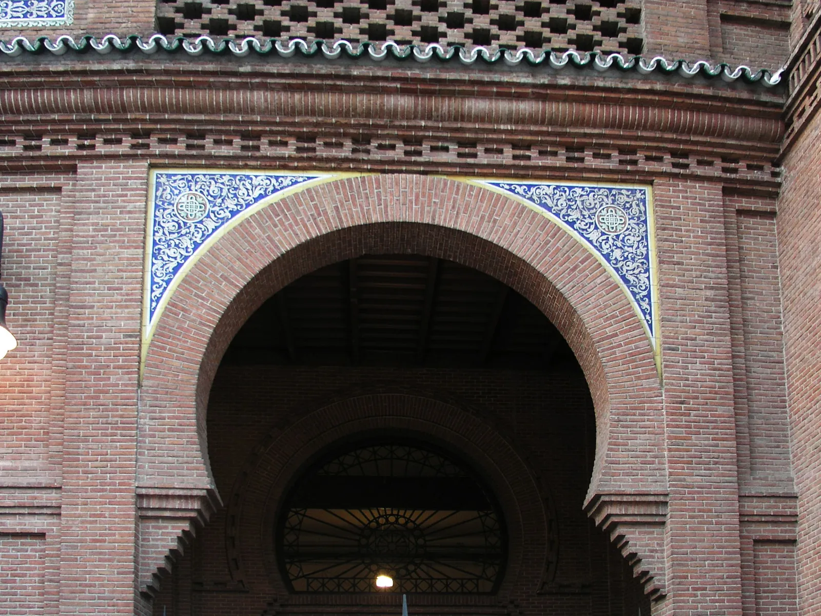 Brick horseshoe arch at Las Ventas framed by white and blue tiles with a brick lattice above