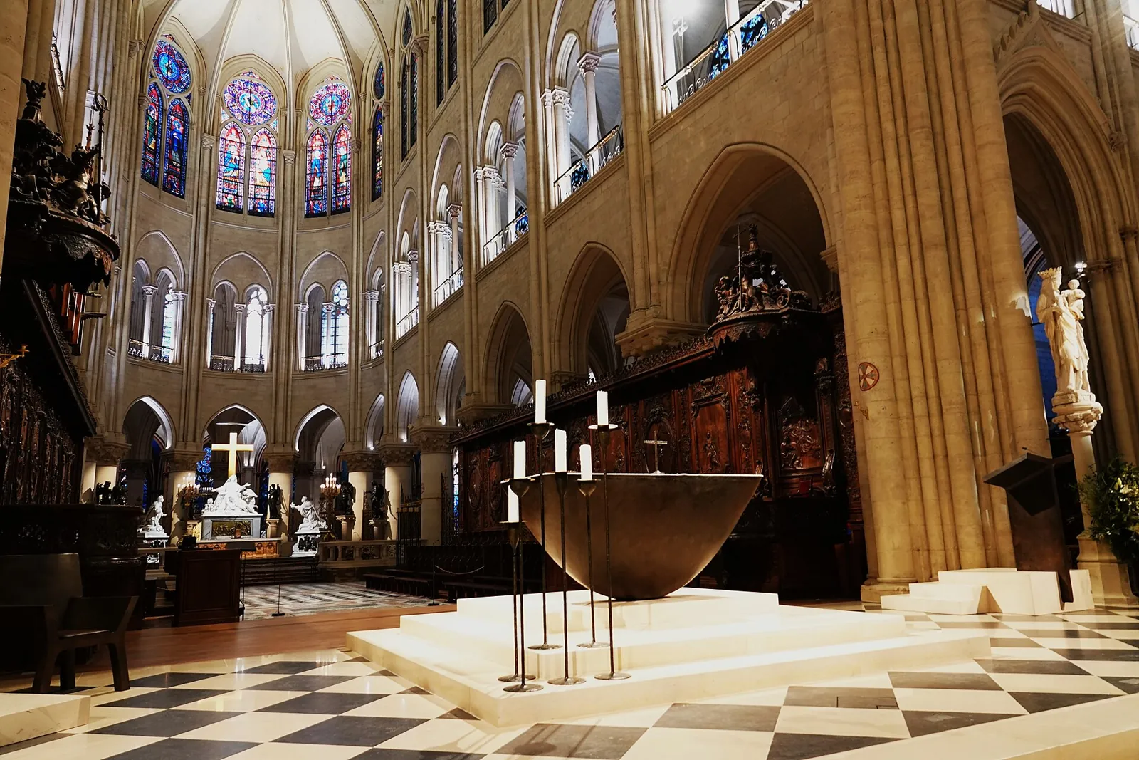 The choir of Notre-Dame with the bronze altar on a pale platform, the carved wooden stalls and the apse windows behind