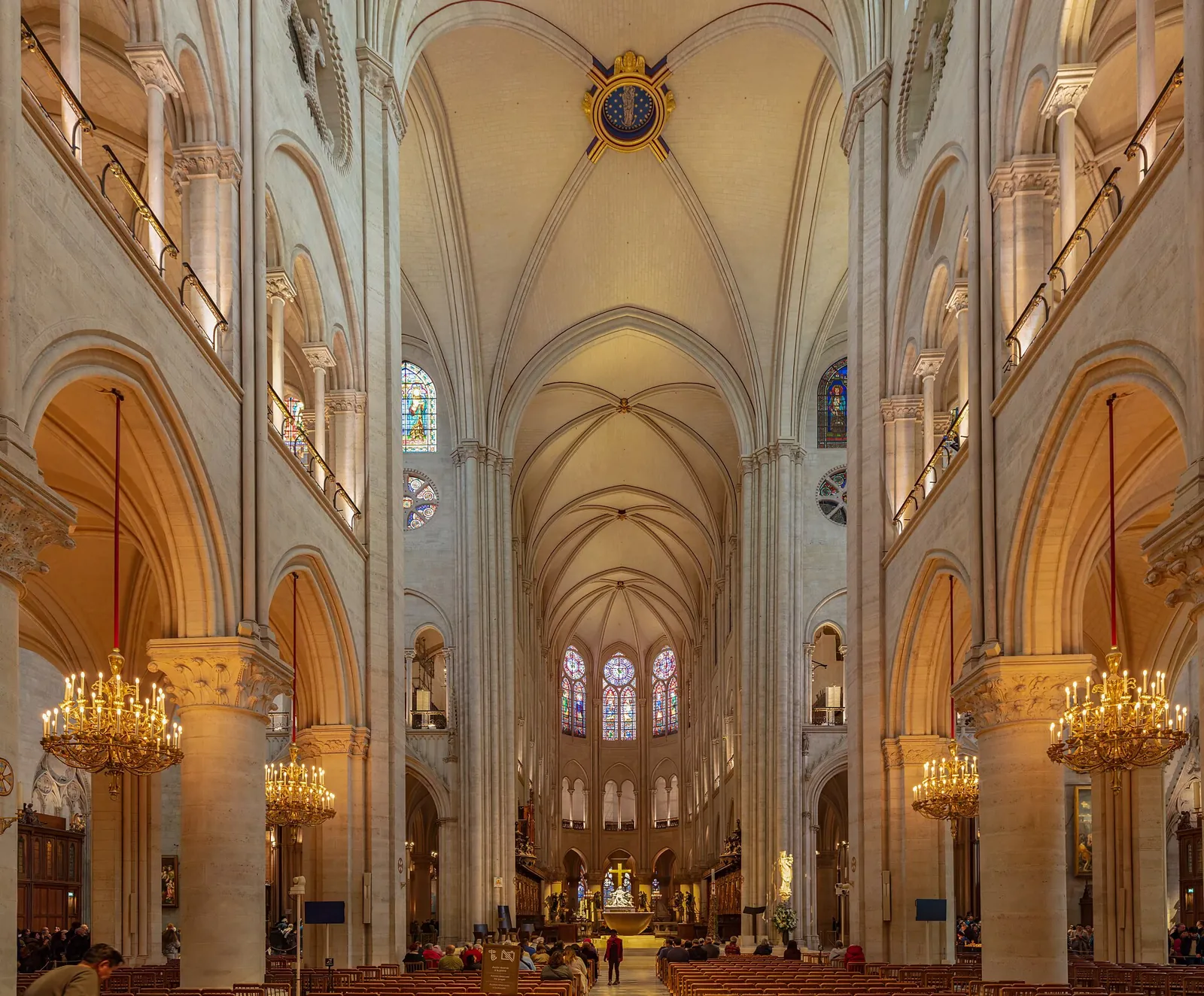 The restored nave of Notre-Dame de Paris, with pale clean stone, rib vaults, chandeliers and the choir at the far end