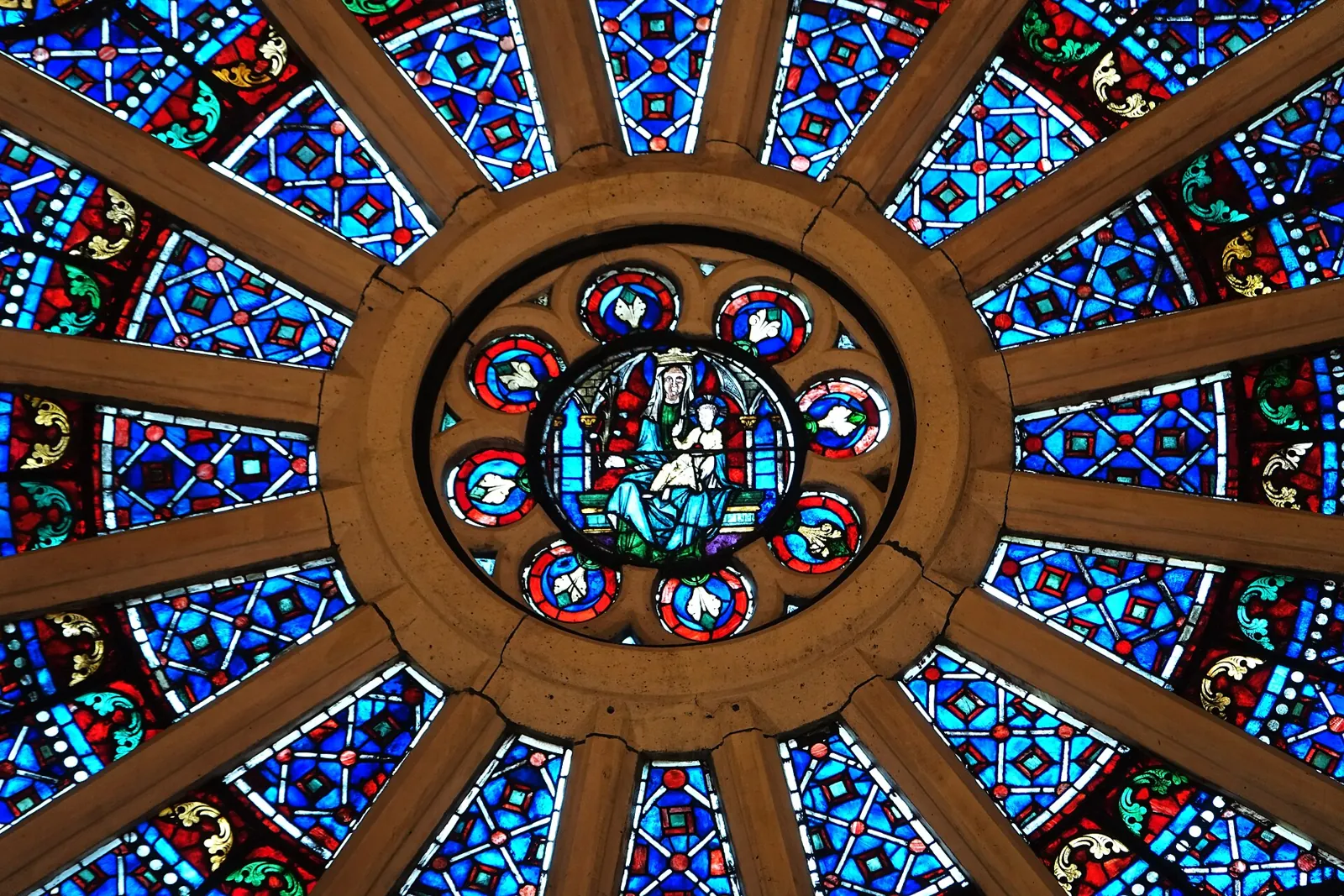 The north rose window of Notre-Dame seen from inside, with blue and red stained glass in rings around a central figure