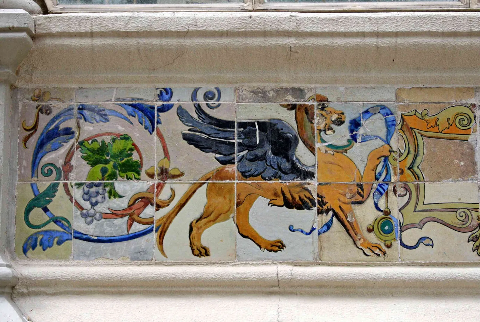 Coloured tile frieze at the base of the Palacio de Cristal with a winged griffin among bunches of grapes and blue scrolls