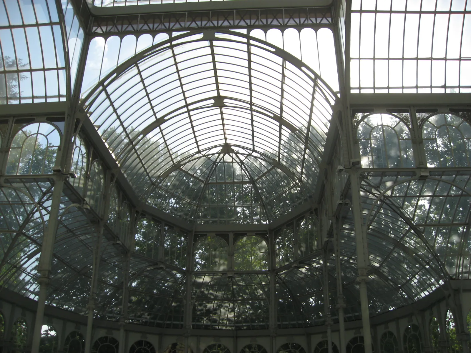Inside the Palacio de Cristal looking up: the glass dome and vaults held by a pale green iron frame