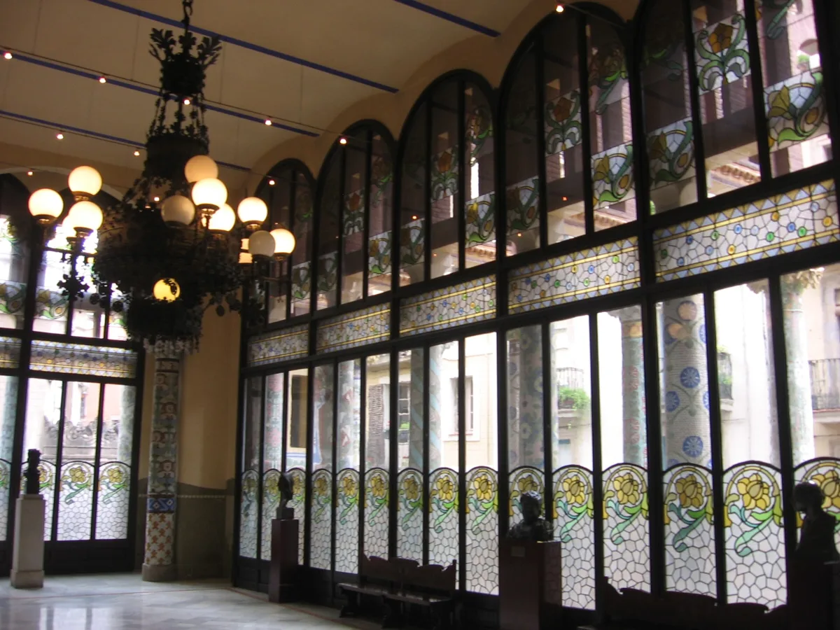 The Sala Lluís Millet at the Palau de la Música Catalana, a hall with tall stained-glass windows with floral motifs and a chandelier