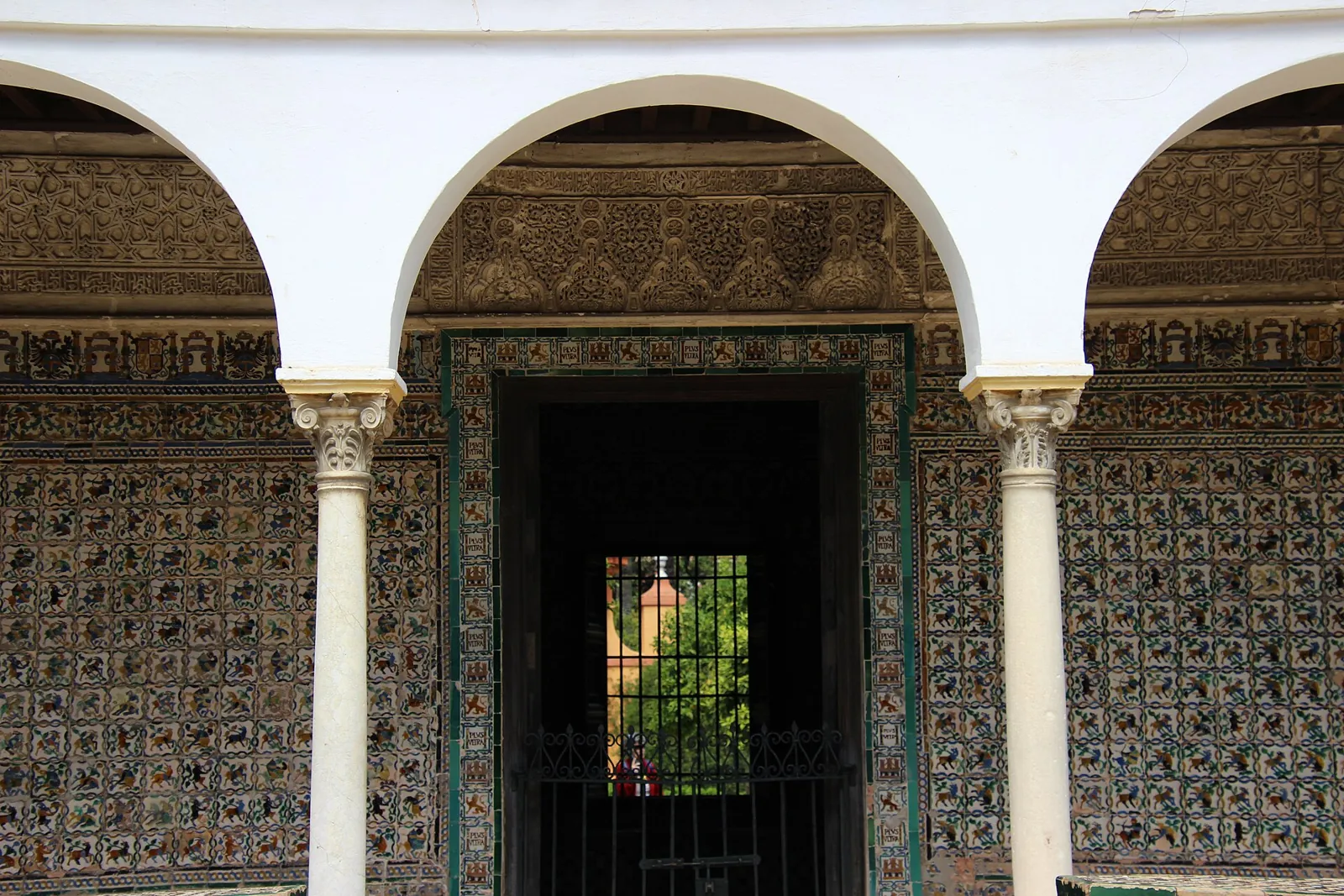 The Pavilion of Charles V in the gardens of the Real Alcázar of Seville: white arches on marble columns in front of walls covered in patterned 16th-century tiles
