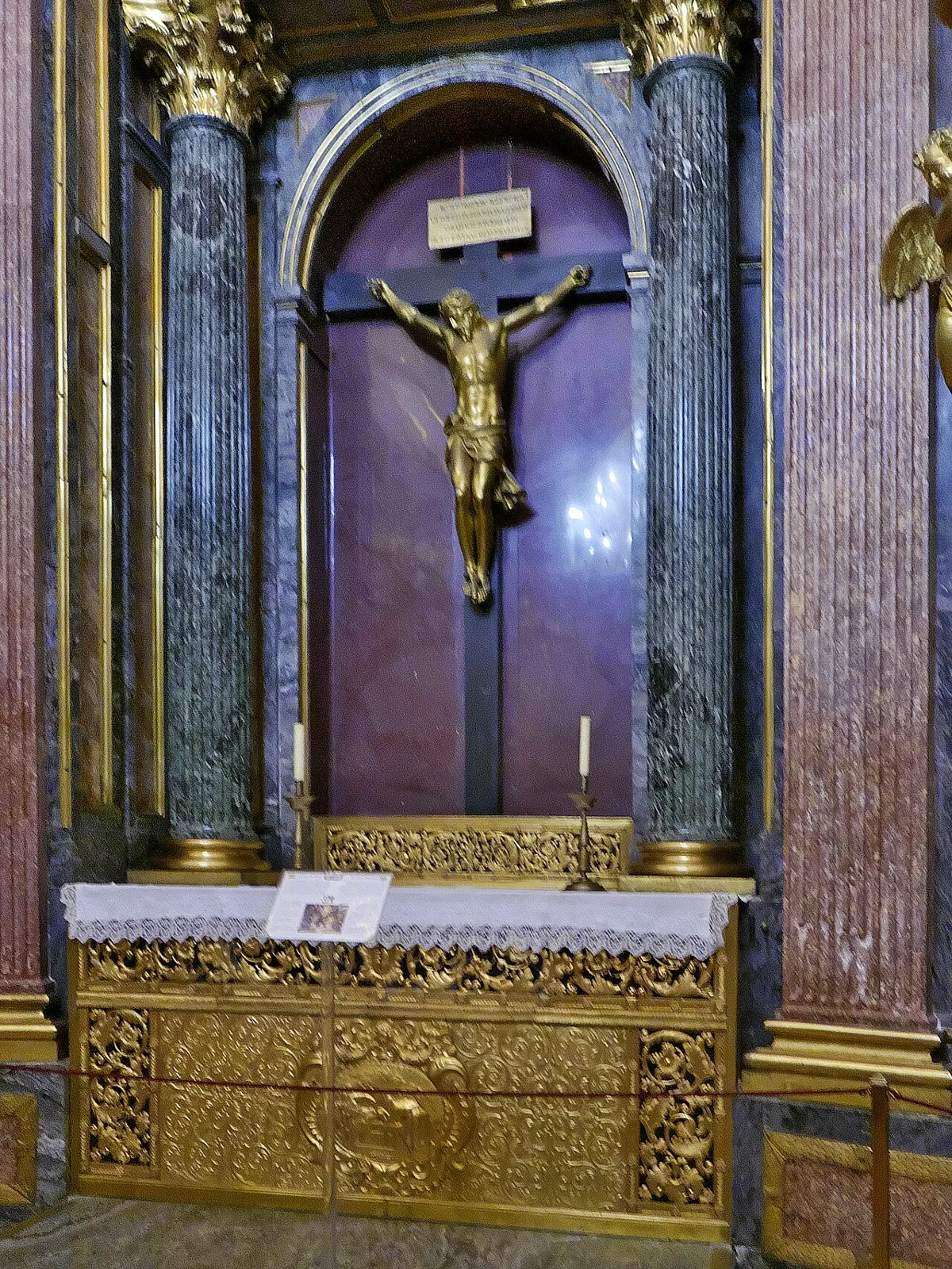 Altar of the Royal Pantheon at El Escorial: a crucified Christ between marble columns and an altar table in gilded bronze