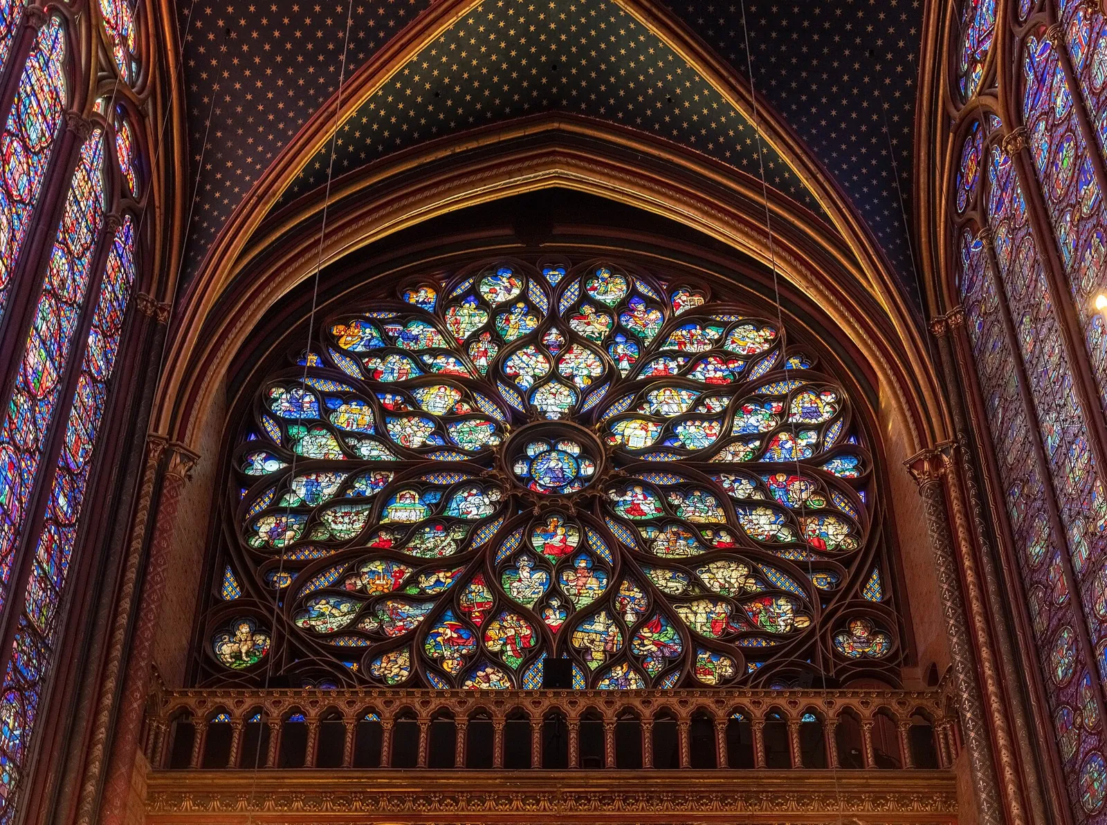 The Apocalypse rose window of the Sainte-Chapelle seen from inside, with green, yellow and blue glass set in flame-like tracery