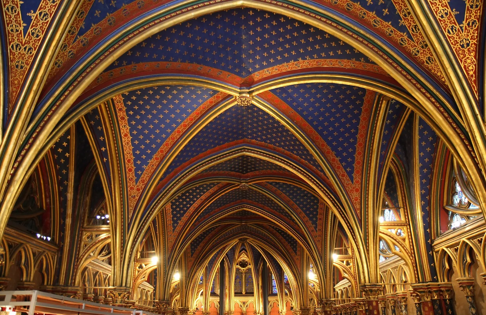 The lower chapel of the Sainte-Chapelle, with blue vaults scattered with gold fleurs-de-lis and arches painted red and gold