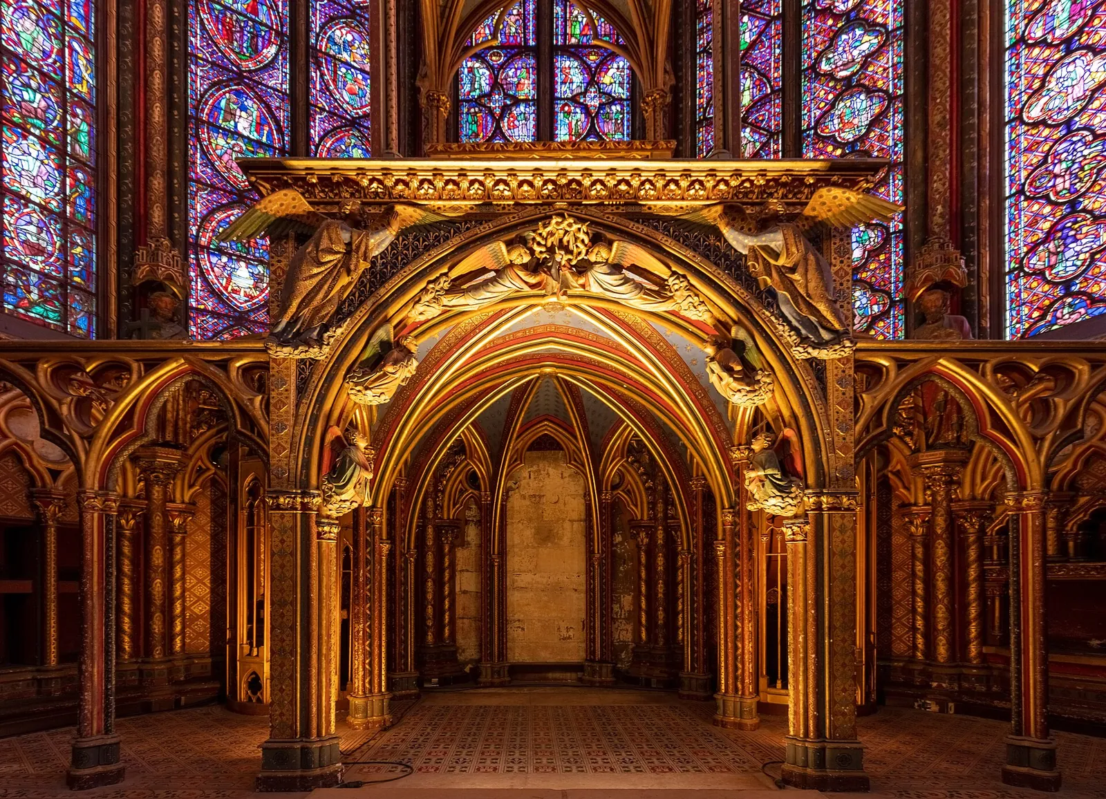 The relic tribune in the apse of the upper chapel of the Sainte-Chapelle, a gilded canopy with Gothic arches beneath the stained glass