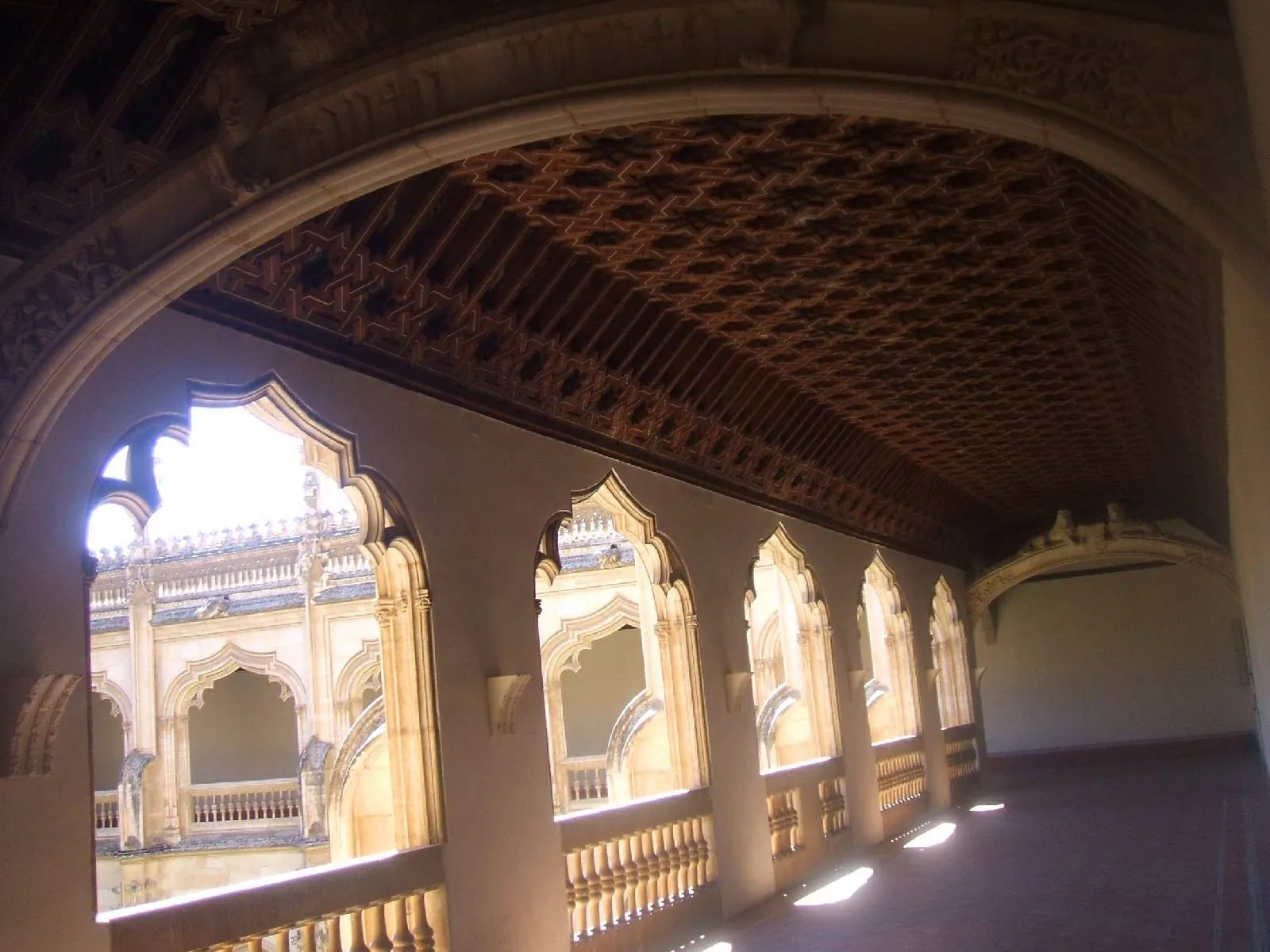 The upper cloister walk of San Juan de los Reyes, with its carved wooden ceiling and the arches looking down into the courtyard