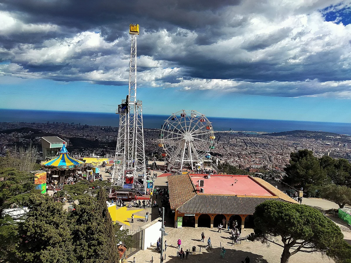 The Tibidabo Amusement Park seen from the terrace of the temple: a tall ride tower, the Giradabo Ferris wheel and Barcelona down to the sea